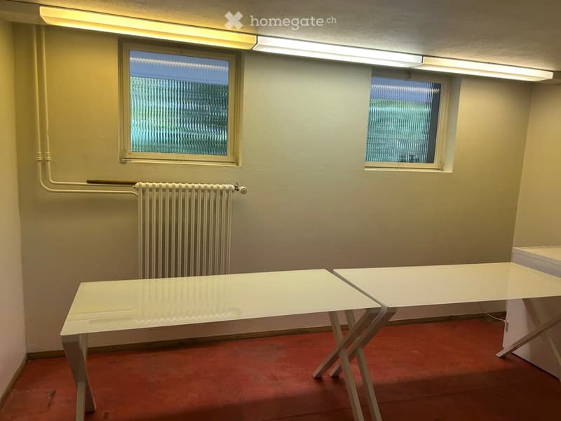 Empty room with two white tables, radiator, and two windows with frosted glass.
