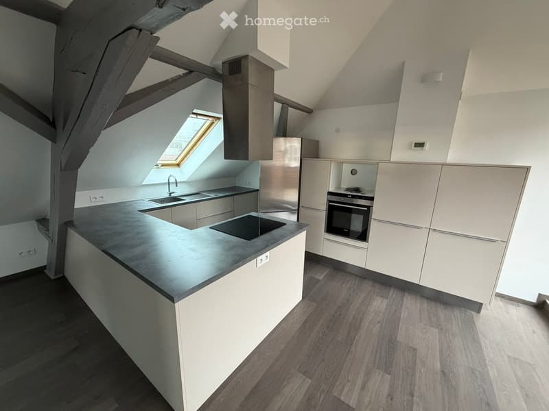 Modern kitchen with white cabinets, stainless steel appliances, and a dark countertop. Features a sink, faucet, refrigerator, and oven.