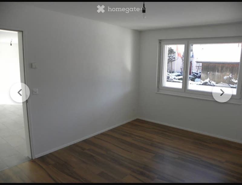 Empty room with wooden flooring, white walls, and large windows showing a snowy outdoor view. No furniture or equipment present.