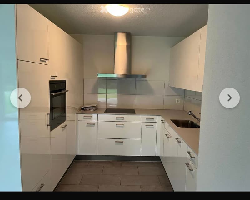 Modern kitchen with white cabinets, stainless steel appliances, and a central island.