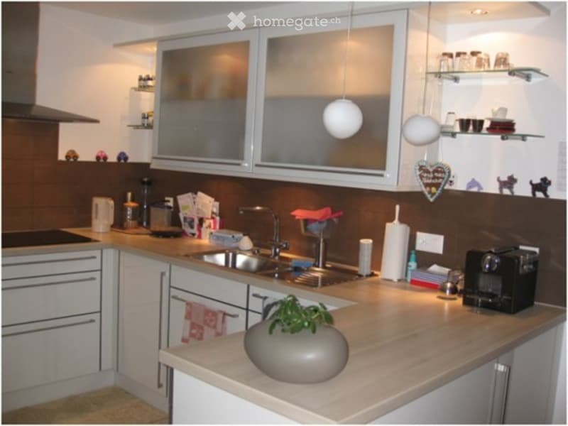 Modern kitchen with white cabinets, stainless steel sink, microwave, and various kitchen items on the counter.