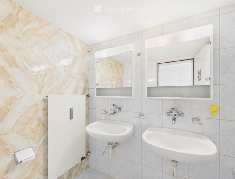 Modern bathroom with two sinks, mirrored cabinets, and marble-style tiles.