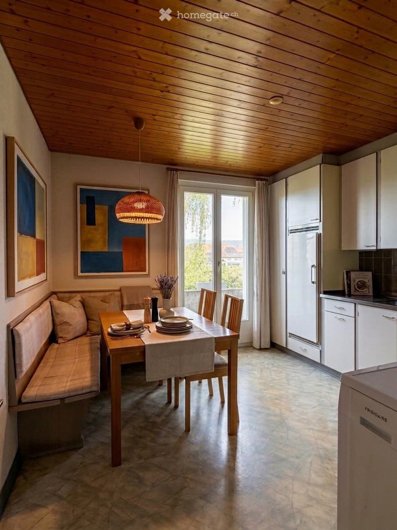 Dining area with a wooden table, bench seating, and chairs, integrated with a modern kitchen featuring white cabinets and stainless steel appliances.