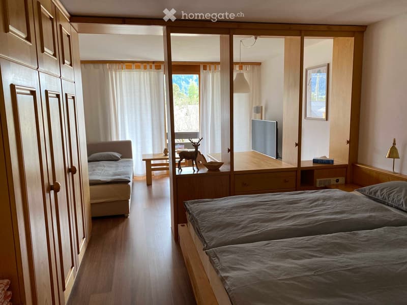 two single beds, wooden wardrobe, window with curtains, TV, decorative piece