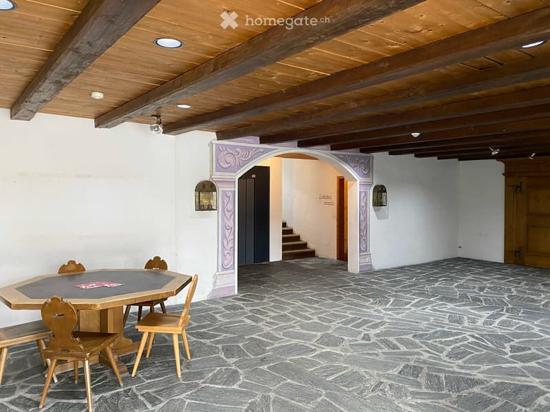 Stone floor, wooden ceiling beams, table and chairs, staircase, door to another room