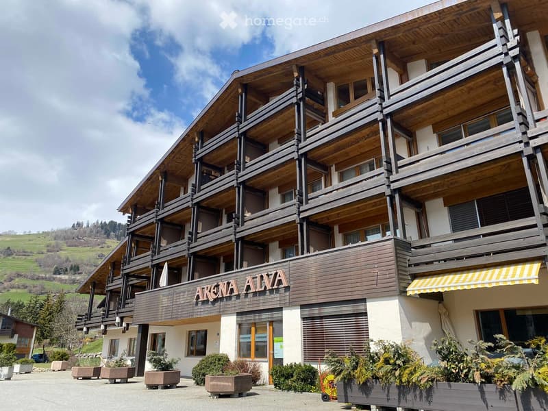 Modern building with wooden exterior, multiple floors with balconies, a yellow awning