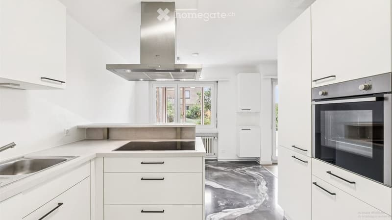 Modern kitchen with white cabinets, stainless steel appliances, and a marble-effect floor.