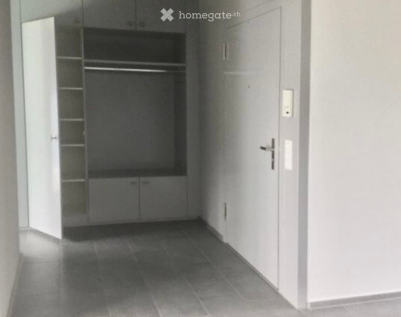 Empty hallway with tiled floor, white walls, and built-in closet with shelves and drawers.