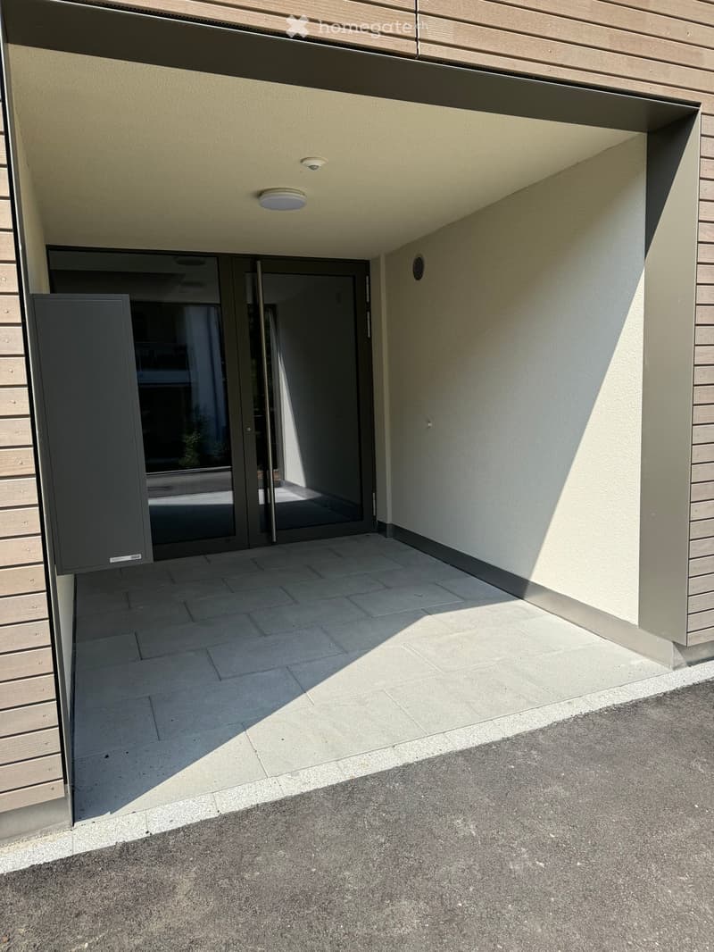 Modern covered entrance area with tiled flooring, glass doors, and recessed lighting.