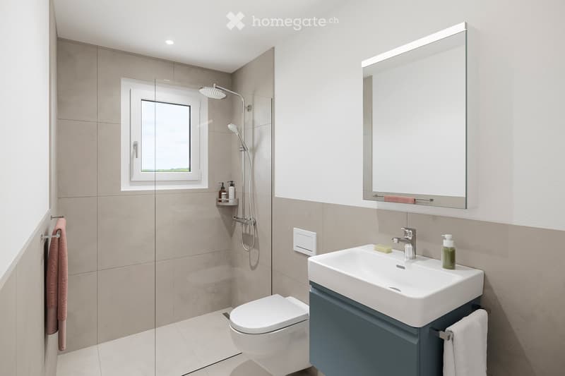 Modern bathroom with a white toilet, sink, and shower. Features a large mirror with built-in lighting, a window, and tiled walls.