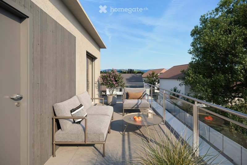 Modern balcony with grey sofa, armchair, round table, and potted plant, overlooking a scenic landscape.