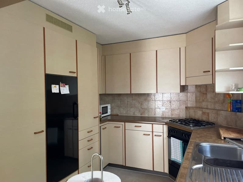 Modern kitchen with light-colored cabinets, stainless steel appliances, and a tiled backsplash.