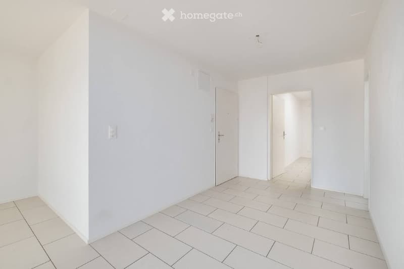 Empty room with white walls, tiled floor, and two doors leading to other spaces.