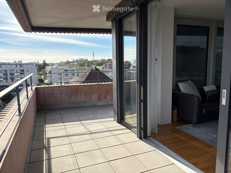 Balcony with tiled floor, metal railing, and a view of the cityscape and surrounding buildings.