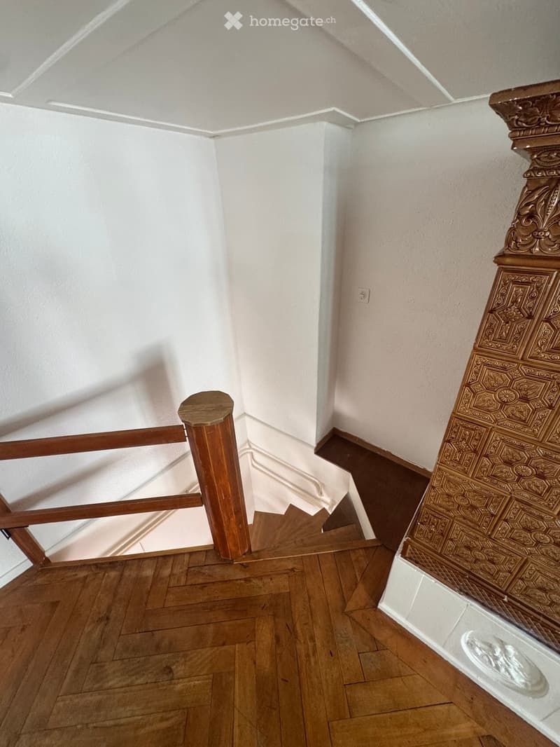Staircase with wooden steps, ornate wooden handrail, and decorative balusters leading to an upper level.