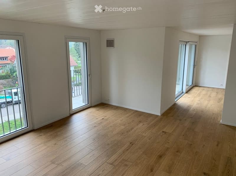 Empty room with wooden flooring, large sliding glass doors, and white walls.