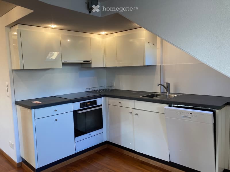 Modern kitchen with white cabinets, black countertops, an oven, a dishwasher, and a sink with a faucet.
