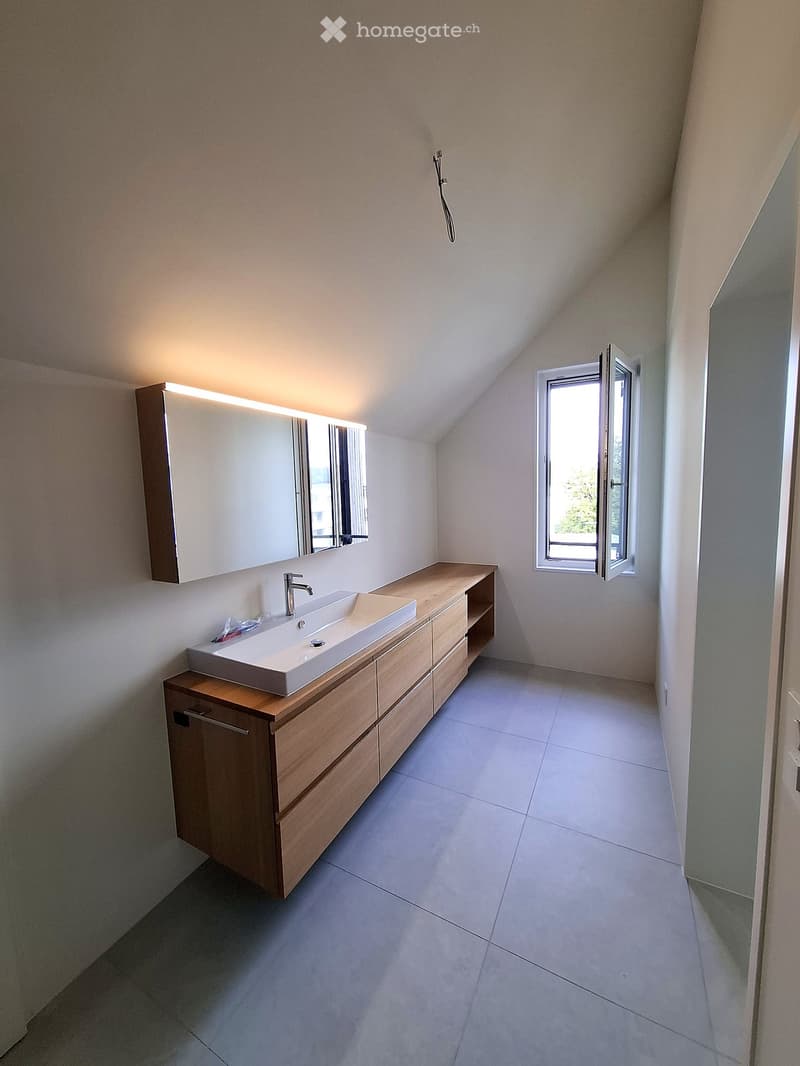 Modern bathroom with a white sink, wooden cabinet, large mirror, and a window with an open shutter.