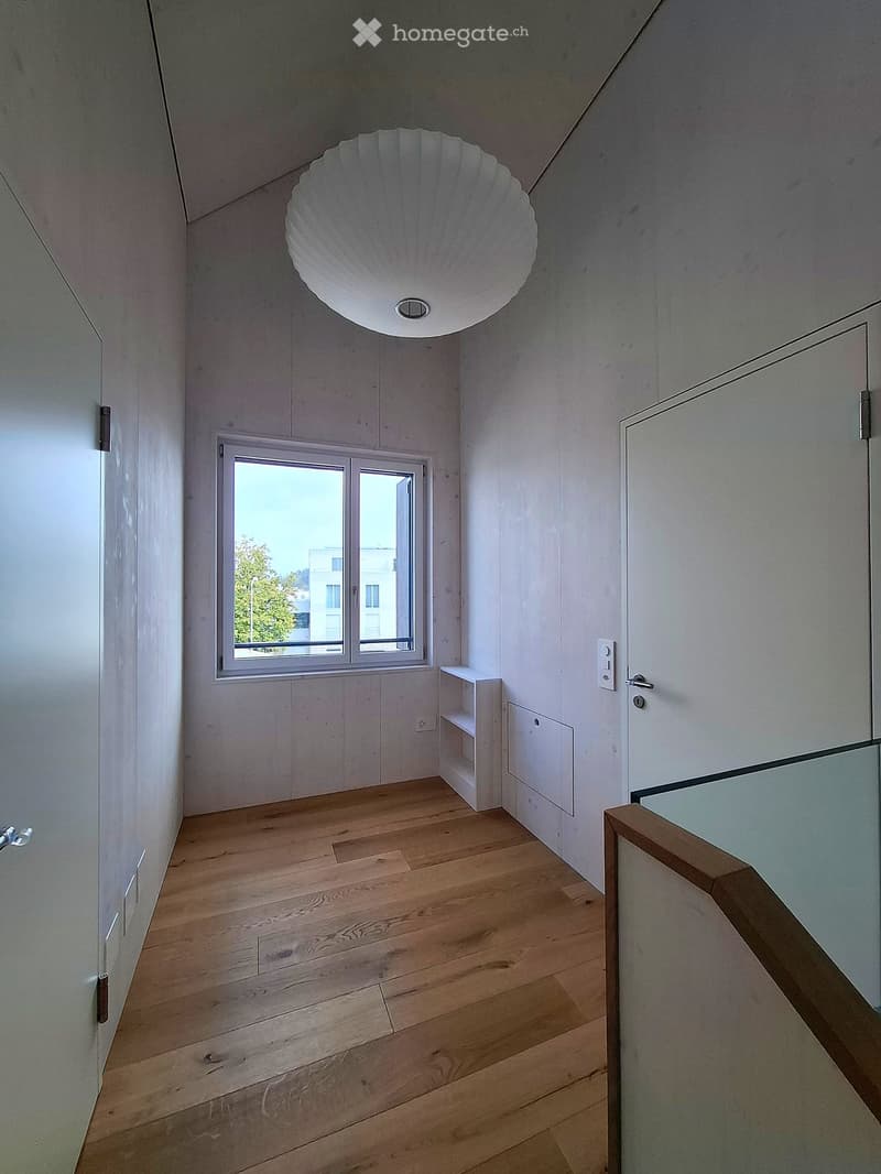 Modern hallway with wooden flooring, white walls, a large window, and a unique shell-shaped light fixture.