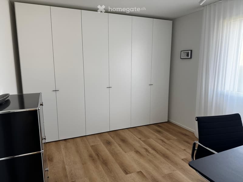 Large walk-in closets, desk chair, black desk, picture frame, wooden flooring, white walls