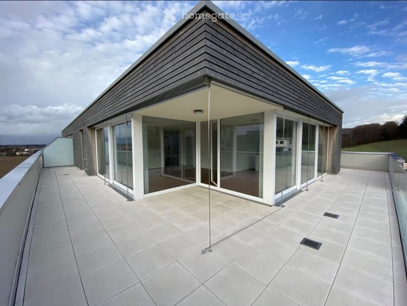 Modern rooftop terrace with large glass sliding doors, tiled floor, and a sleek, contemporary design.