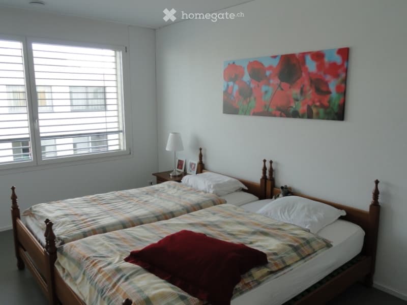 A twin-sized bedroom with two single beds, a nightstand, a lamp, and a colorful painting on the wall.