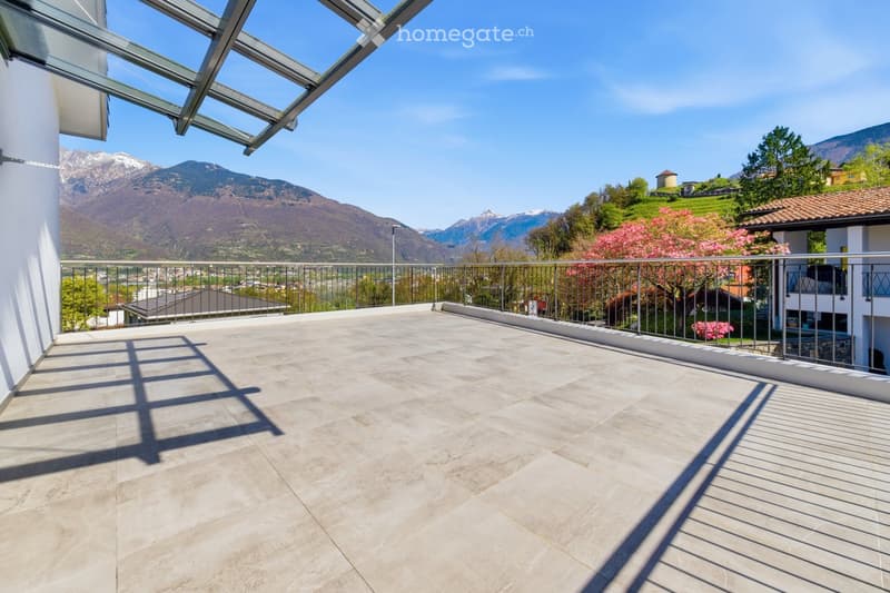 Spacious balcony with modern glass roof, tiled floor, metal railing, and scenic mountain view.