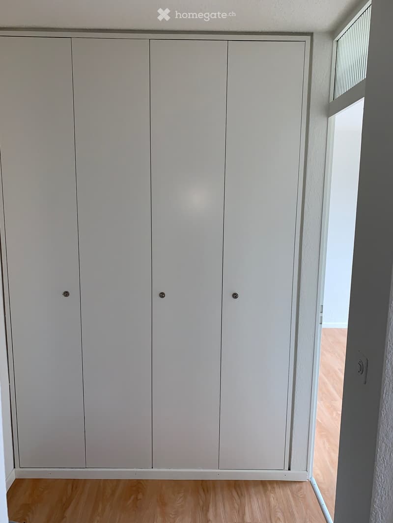 Empty room with light wooden flooring and white built-in wardrobes. The room has a simple, clean design with no visible furniture or personal items.
