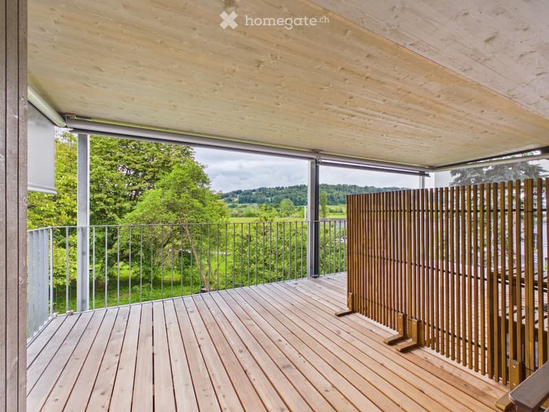 Wooden deck with metal railing, wooden privacy screen, and scenic view of greenery.
