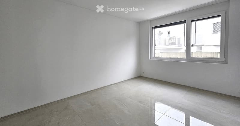 Empty room with white walls, tiled floor, and large window with a view of a neighboring building.