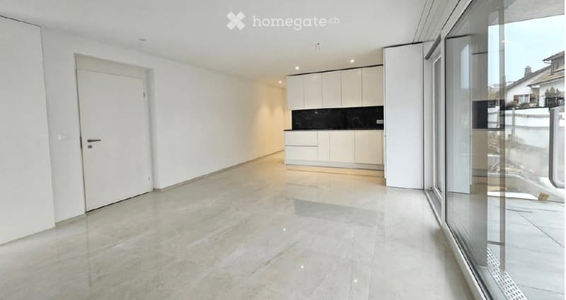 Empty room with white walls, light grey tiled floor, white cabinetry, and large glass window offering a view of the outside.