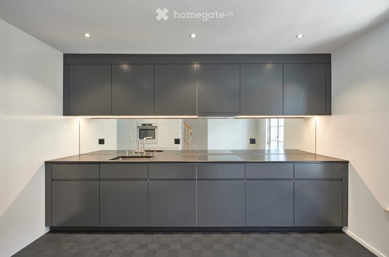 Modern kitchen with dark grey cabinets, stainless steel sink, and built-in oven.