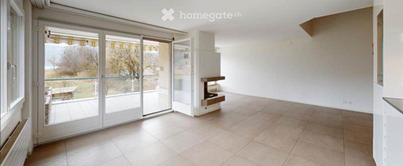 Empty living space with large sliding glass doors leading to a balcony, tiled floor, and a small built-in fireplace.
