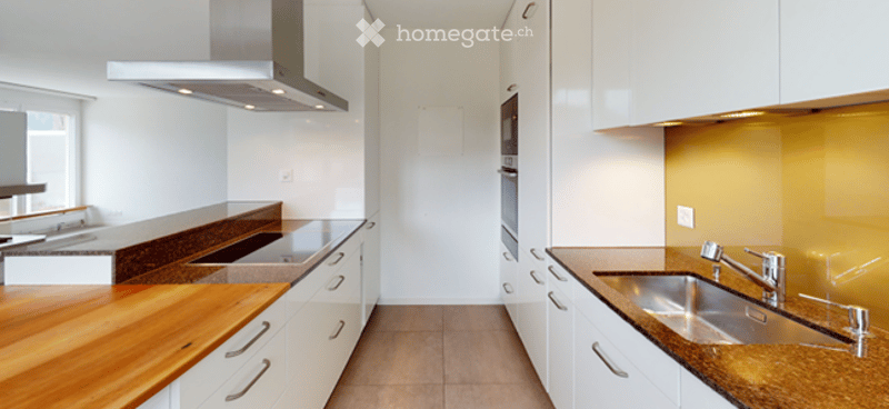 Modern kitchen with white cabinets, wooden countertops, stainless steel sink, and range hood.
