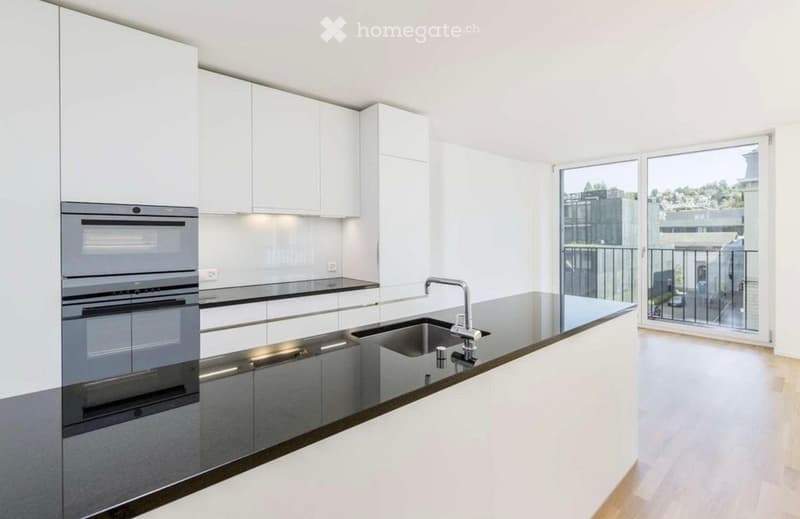 Modern kitchen with white cabinets, stainless steel appliances, and a large window offering a view of the city.