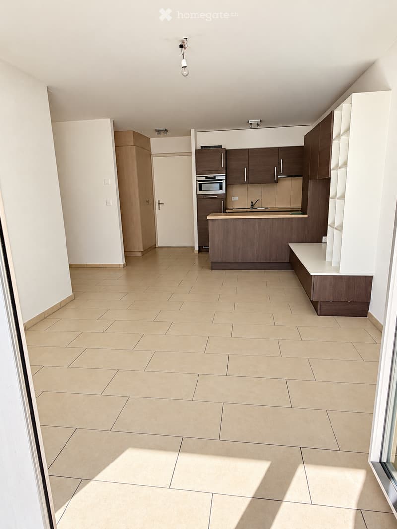 Empty kitchen with tiled floor, fitted cabinets, and a countertop. No furniture or appliances are present.