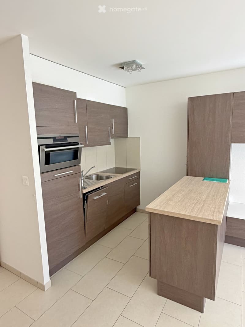 Modern kitchen with wooden cabinets, stainless steel oven, sink, and a central island.