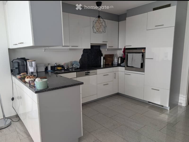 Modern kitchen with white cabinets, granite countertop, stainless steel appliances, and a central island.