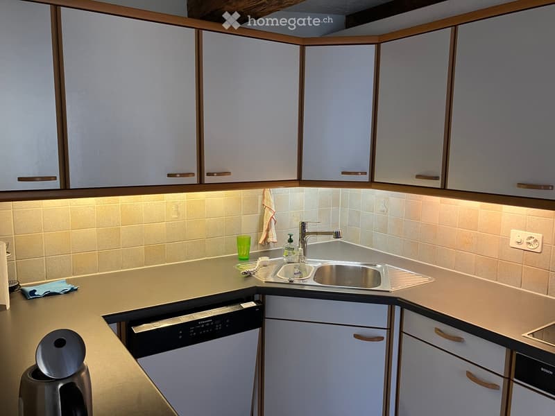 Modern kitchen with white cabinets, stainless steel sink, dishwasher, and electric kettle on the counter.
