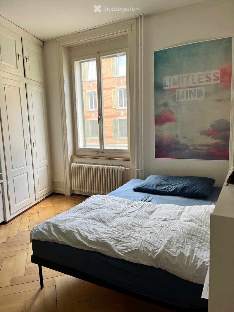Bedroom with a single bed, wooden flooring, radiator, and a large poster on the wall.