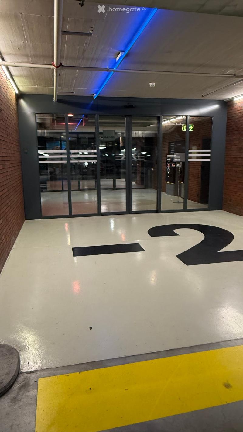 Modern hallway with glass doors, white walls, and a large directional sign reading "2" on the floor.