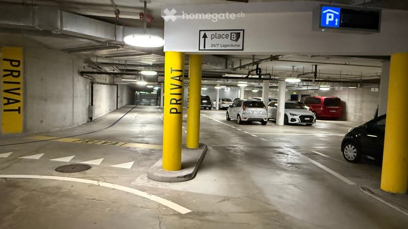 Underground parking area with several parked cars, yellow pillars, and signage indicating private access and storage area.