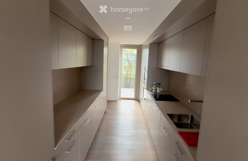 Modern kitchen with light grey cabinets, stainless steel appliances, and a clean, minimalist design. Features a sink, stove, and ample cabinet space.