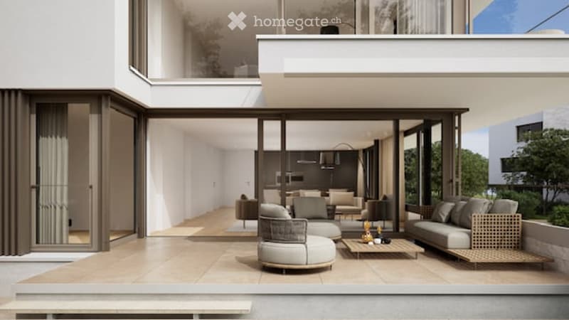 Modern, minimalist living room with large glass doors leading to a spacious balcony. The room features a grey sofa, a coffee table, a couple of armchairs, and a small ottoman. The balcony has a modern design with a round seating area and a small table.