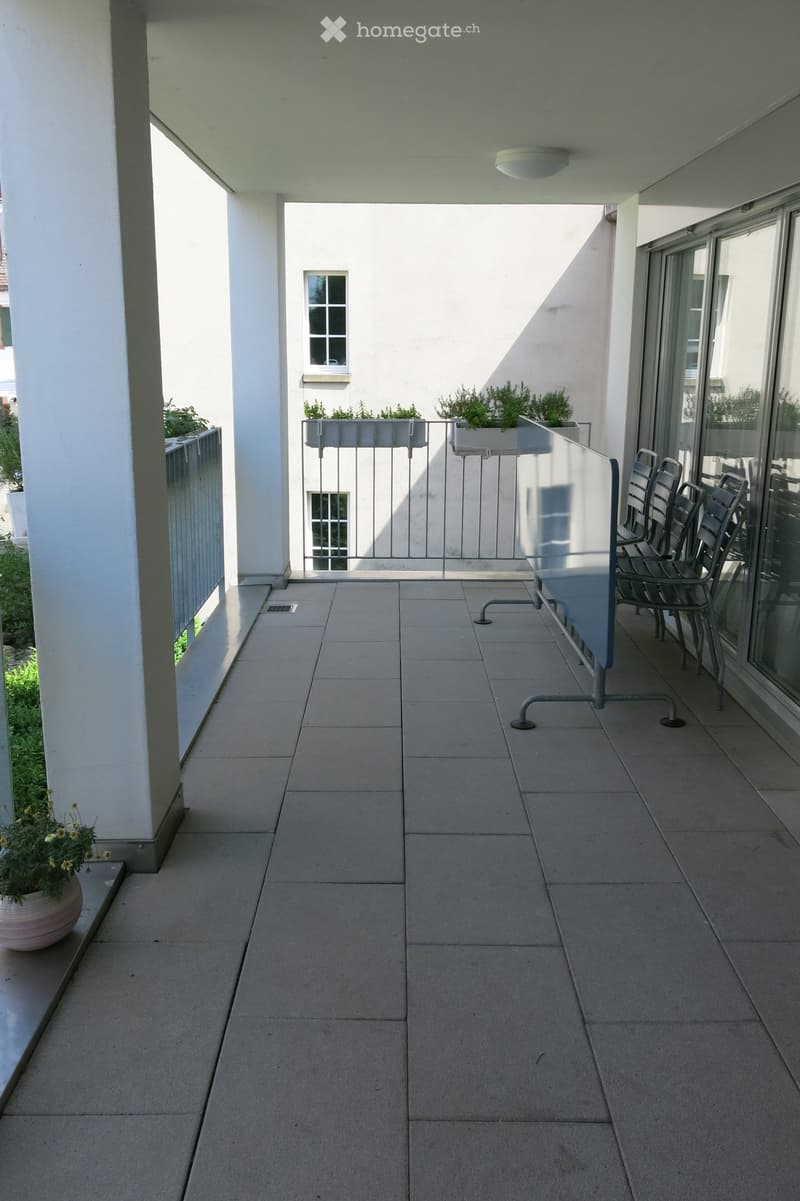 Balcony with tiled floor, metal railing, and several chairs placed near the glass door.
