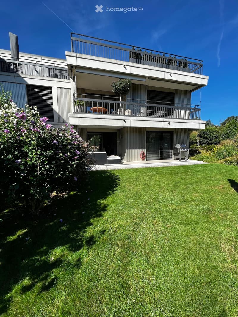 Modern two-story building with balconies, outdoor seating, and a well-maintained lawn.