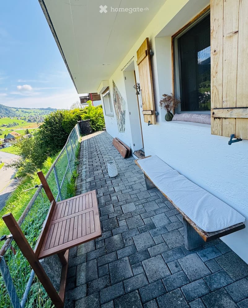 Balcony with a view, featuring a wooden bench, a wooden chair, and a decorative vase.
