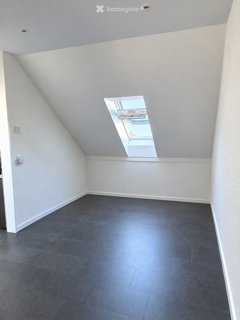Completely empty room with bare walls and dark grey tiled floor. No furniture or equipment.