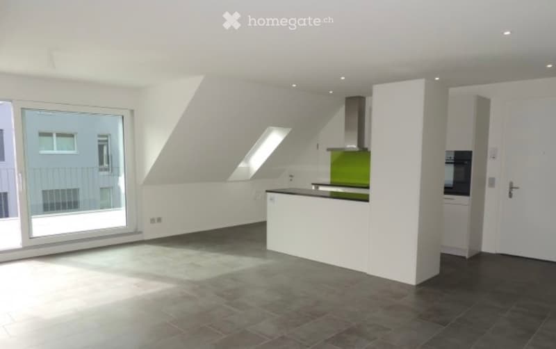 Modern kitchen with white cabinets, green backsplash, kitchen island, and large windows offering a view of the balcony.