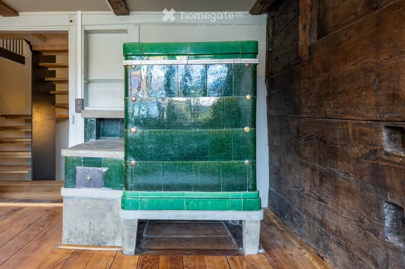 Hallway with wooden flooring, green metal bench, staircase leading upwards, and wooden wall paneling.